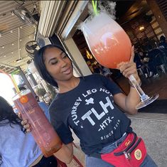 a woman holding up a tall glass filled with liquid