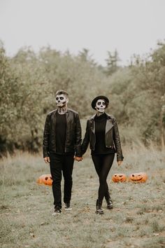 two people in skeleton makeup walking through a field with pumpkins