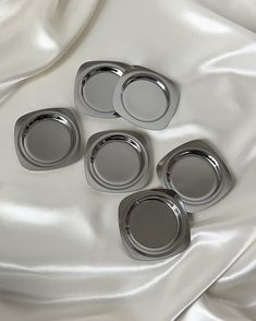 four metal trays sitting on top of a white cloth