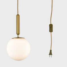 a white ball hanging from a brass colored cord with a light bulb attached to it