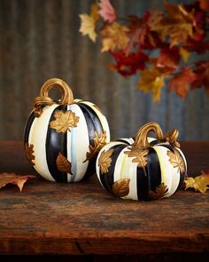 two black and white striped pumpkins sitting next to each other on a wooden table