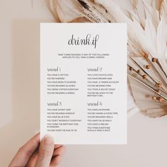 a person holding up a menu with feathers on the table next to it and a feather fan