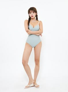 a woman in a blue one piece swimsuit with her arms crossed posing for the camera