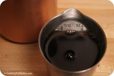 a close up of a coffee pot on a table with a measuring cup next to it