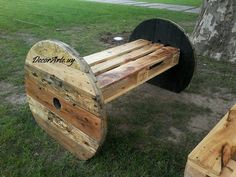 a bench made out of wooden pallets sitting in the grass next to a tree