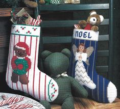 two christmas stockings with angels and a teddy bear sitting next to each other on a table