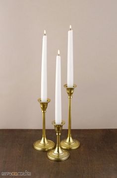 three white candles sitting on top of a wooden table