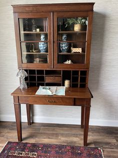 a wooden desk with two glass doors on top of it and a rug in front of it