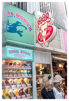 two women are looking in the window of a store with many different items on display