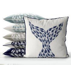 four pillows stacked on top of each other in different colors and patterns, one with a bird design