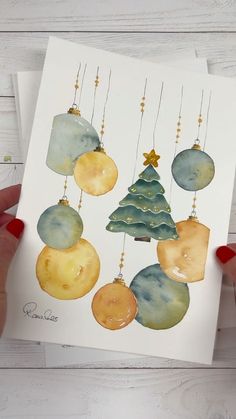 a person holding up a card with christmas ornaments on it