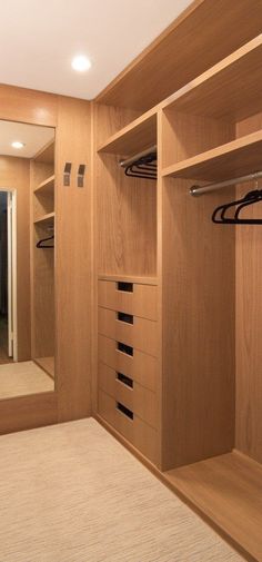 an empty walk - in closet with wooden shelves and drawers