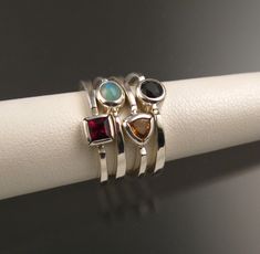 "Set of Four Sterling Silver rings with your choice of premium natural birthstones.(restrictions apply). Size and shape can vary (triangle, round, oval, and square). Stones are between 3.5 and 4.5mm. Four rings are about 8mm wide at the bottom and 12mm at the top. Specify ring size and birthstone preference in a \"note to seller\" at check-out. It is always best to send me a note before ordering to work out the details." Modern Sterling Silver Birthstone Ring With Accent Stones, Silver Trillion-cut Birthstone Ring, Silver Trillion Cut Birthstone Ring, Silver Trillion Cut Ring With Birthstone, Sterling Silver Stackable Rings With Gemstone Accents, Fine Jewelry Sterling Silver Stackable Rings With Gemstone Accents, Trillion Cut Sterling Silver Ring With Gemstone, Silver Stackable Rings With Gemstone Accents For Anniversary, Sterling Silver Stackable Rings With Accent Stones