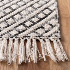 a black and white rug with tassels on top of wooden floor next to wood flooring