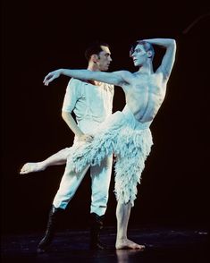 two dancers in white tutus and feathered skirts, one holding the other's leg