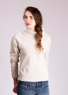 a woman with long hair wearing jeans and a turtle neck sweater