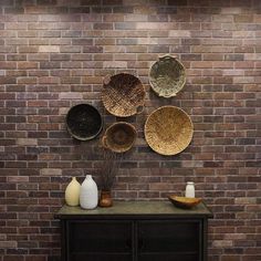 a brick wall with baskets on it and vases sitting on top of the table