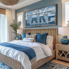 a bedroom with blue and white bedding, pillows and decor on the wall above it