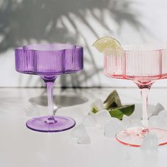 three different colored wine glasses sitting on top of a white table next to each other