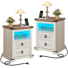 two white nightstands with blue lights and plants on each side, one is turned on