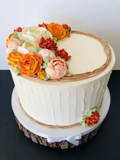 a white cake with orange and red flowers on it's top, sitting on a table