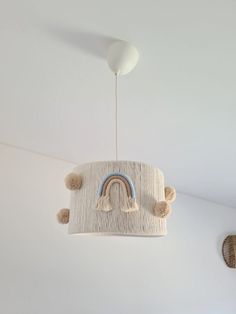 a light fixture with a rainbow hanging from it's side in a white room