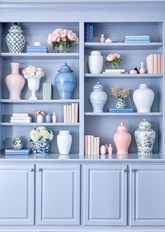 a blue bookcase filled with lots of vases and flowers on top of it