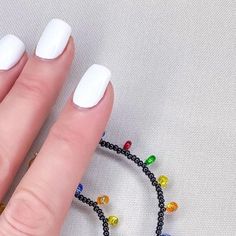 a woman's hand with white nails and beaded bracelet