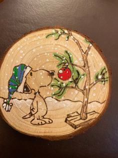 a painted wooden plate with a dog and apple tree on the front, sitting on a table