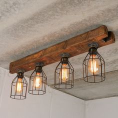 three light fixtures hanging from the ceiling in a room with concrete walls and exposed wood beams