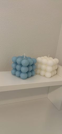 two candles sitting on top of a white shelf