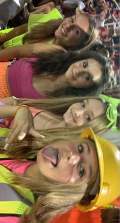 four girls are posing for the camera in front of a group of people wearing hard hats