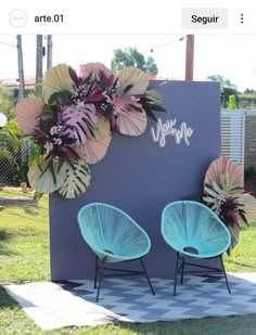 two blue chairs sitting in front of a sign with flowers on it and the words welcome