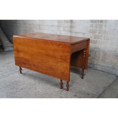 an old wooden desk sitting in front of a brick wall on wheels and legs with one drawer open