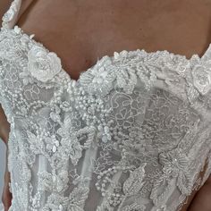 the back of a woman's wedding dress with white flowers and lace on it