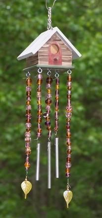 a wind chime hanging from a tree in front of some green grass and trees