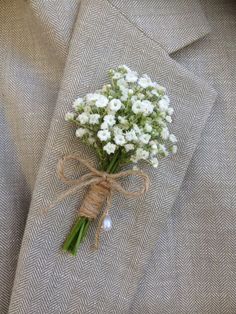 a boutonniere with baby's breath flowers tied to the lapel