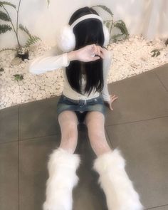 a woman sitting on the ground with her legs crossed and wearing white furry boots,