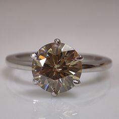 a close up view of a ring with a brown diamond in it on a white surface