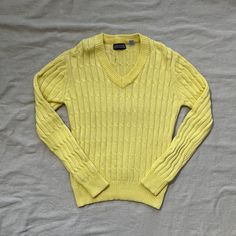 a yellow sweater laying on top of a bed