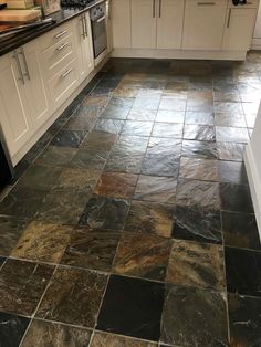 a kitchen with black slate flooring and white cabinets