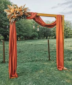 an orange wedding arch decorated with flowers and greenery