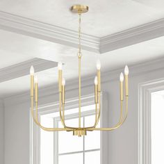 a gold chandelier hanging from the ceiling in a room with white walls and windows