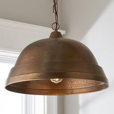 a light fixture hanging from the ceiling in a room with white walls and window sill