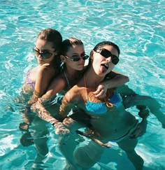 three girls are in the water with their arms around each other