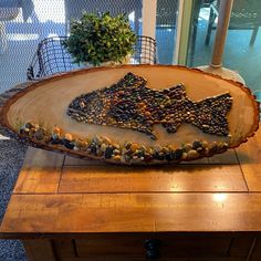 a wooden table topped with a fish shaped tray filled with rocks and pebbles on top of it