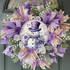 a purple and white wreath with a snowman on it's front door,