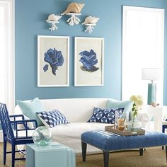 a living room with blue walls and white furniture in the center, along with pictures on the wall