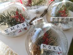 christmas ornaments with words written on them and pine cones in the middle, sitting on a table