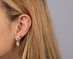 a close up of a person wearing ear piercings with pearls on the end of their ears